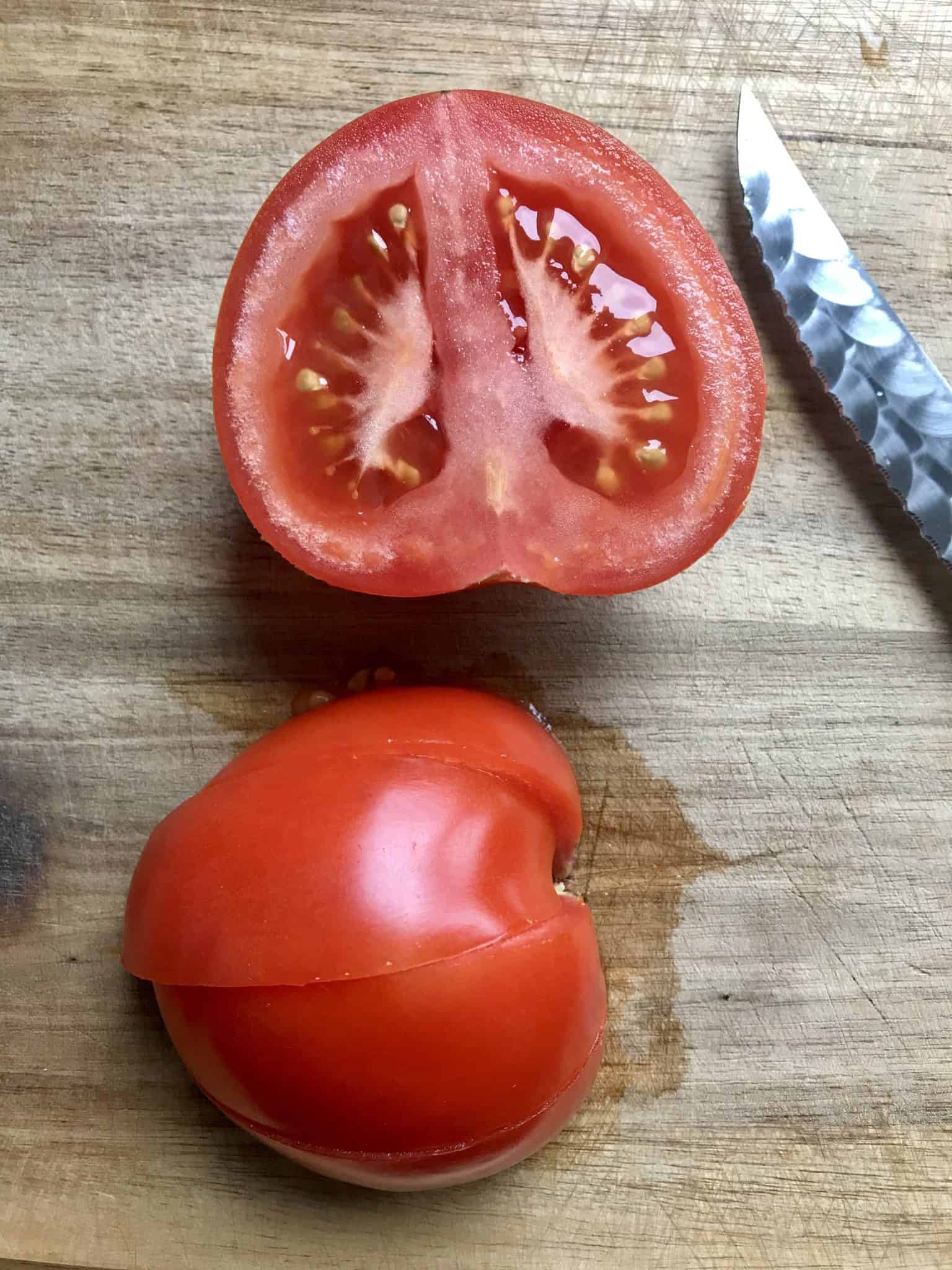Tomato on wooden cutting board sliced in half