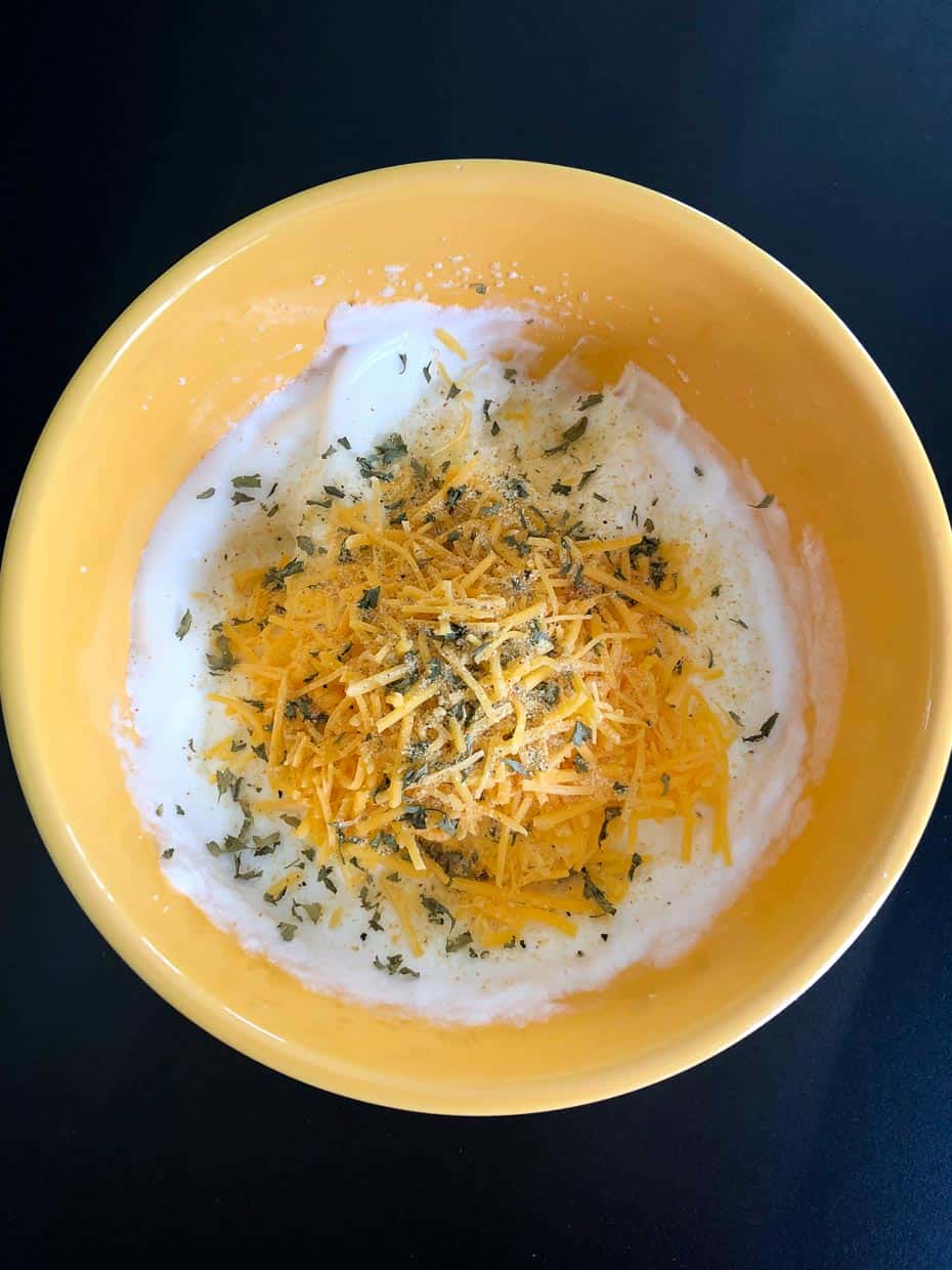 Whipped egg whites with cheese and seasonings in yellow bowl overhead shot