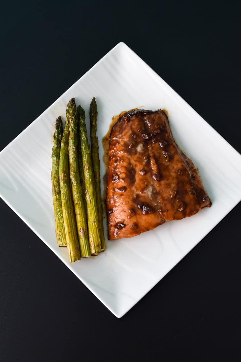 Asparagus served with roasted salmon on white square plate overhead shot