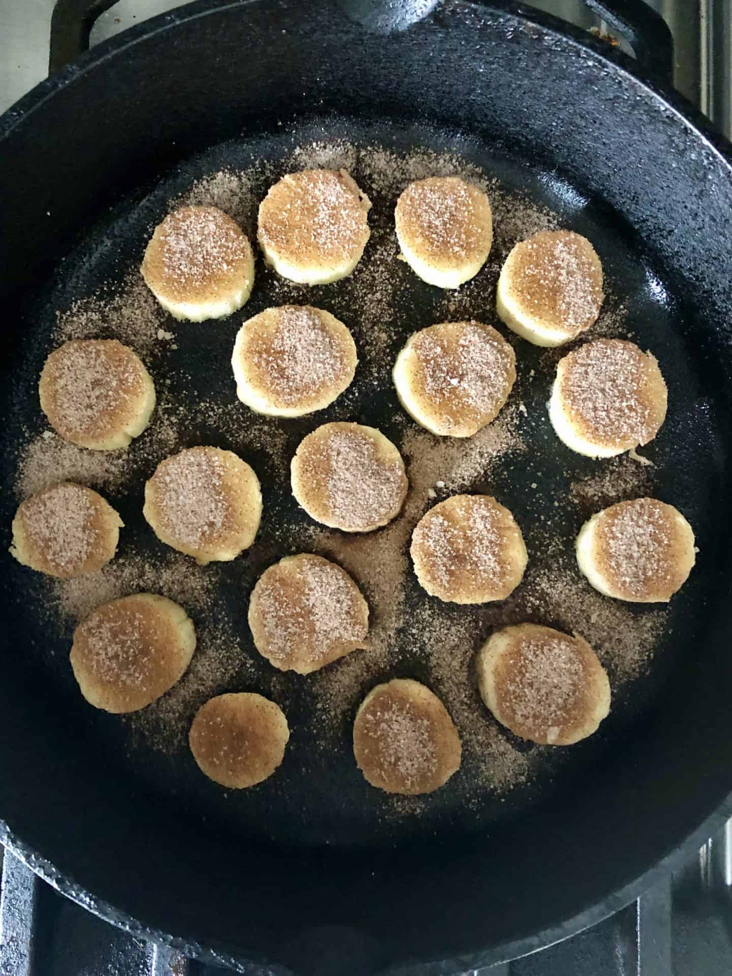 Bananas with cinnamon sugar on top in cast iron pan overhead shot 