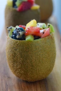 Close up side view of a kiwi stuffed with tropical fruit salad