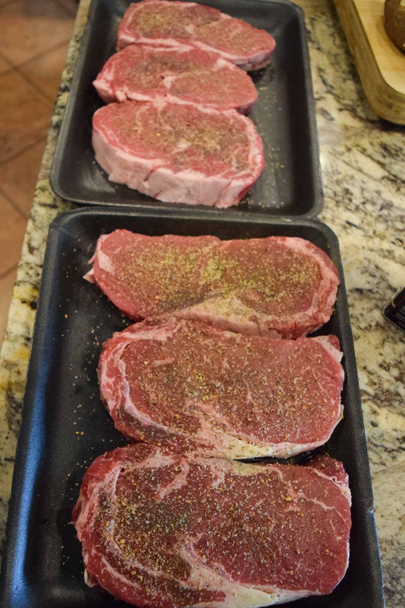 6 steaks covered in seasonings ready to be grilled 