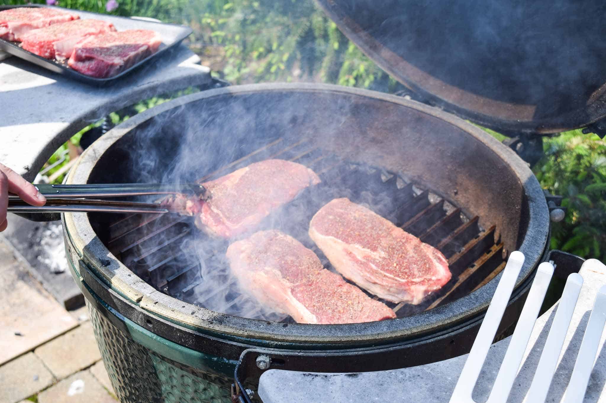 Steaks being flipped with spatula on big green egg grill