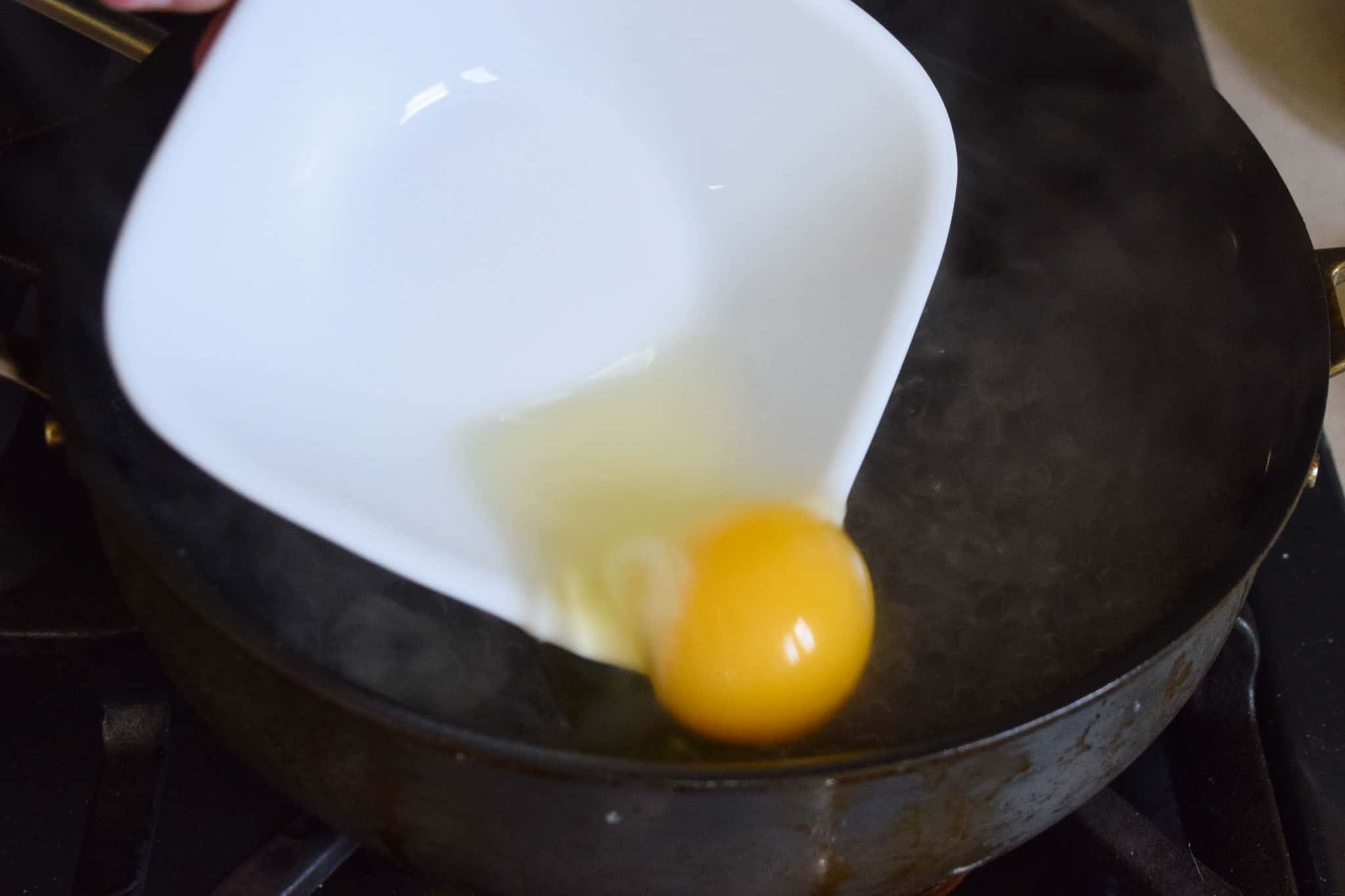 egg being added to boiling water for poaching