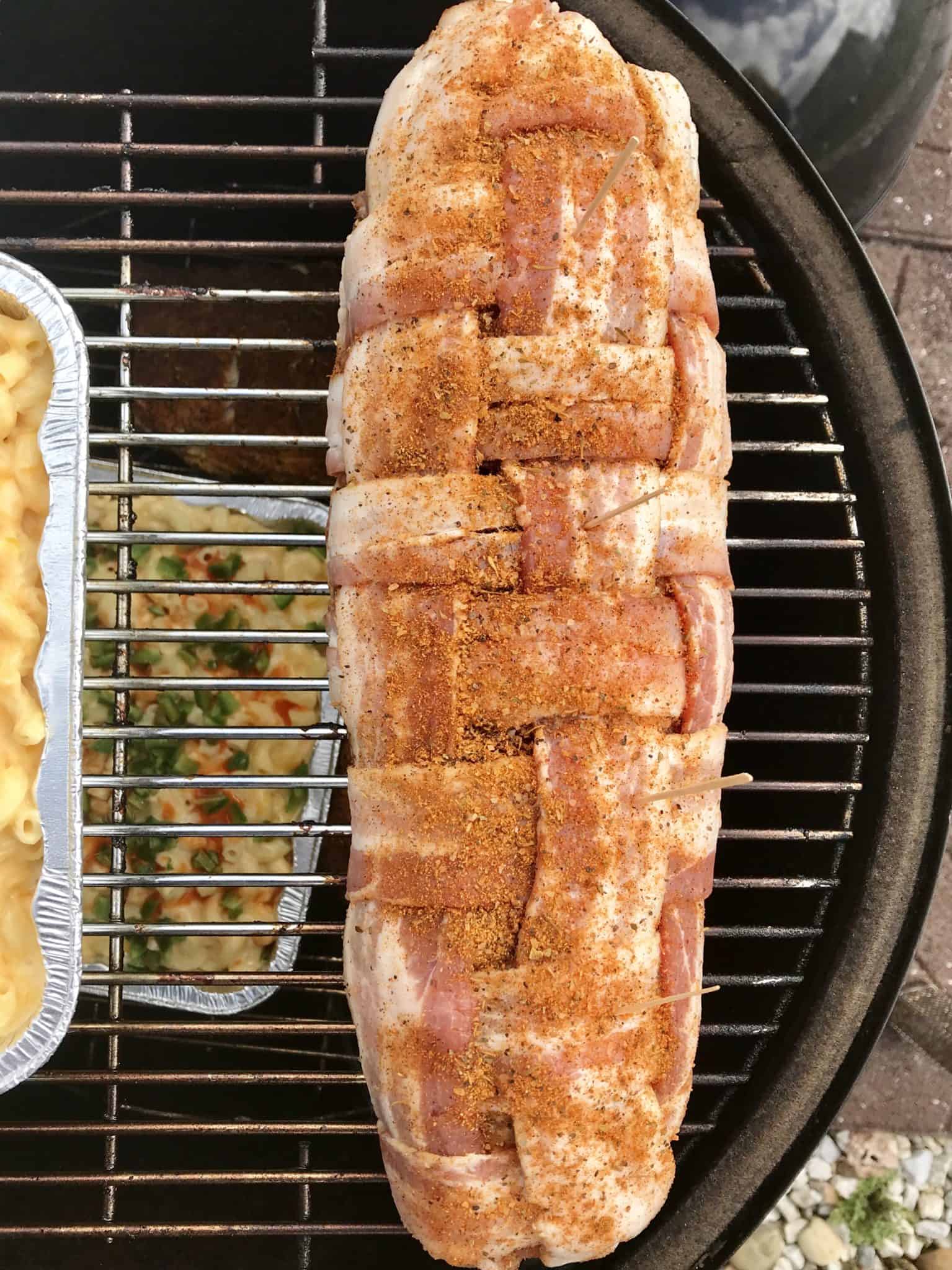 Bacon explosion sitting on weber grill grates with smoked Mac and cheese overhead shot