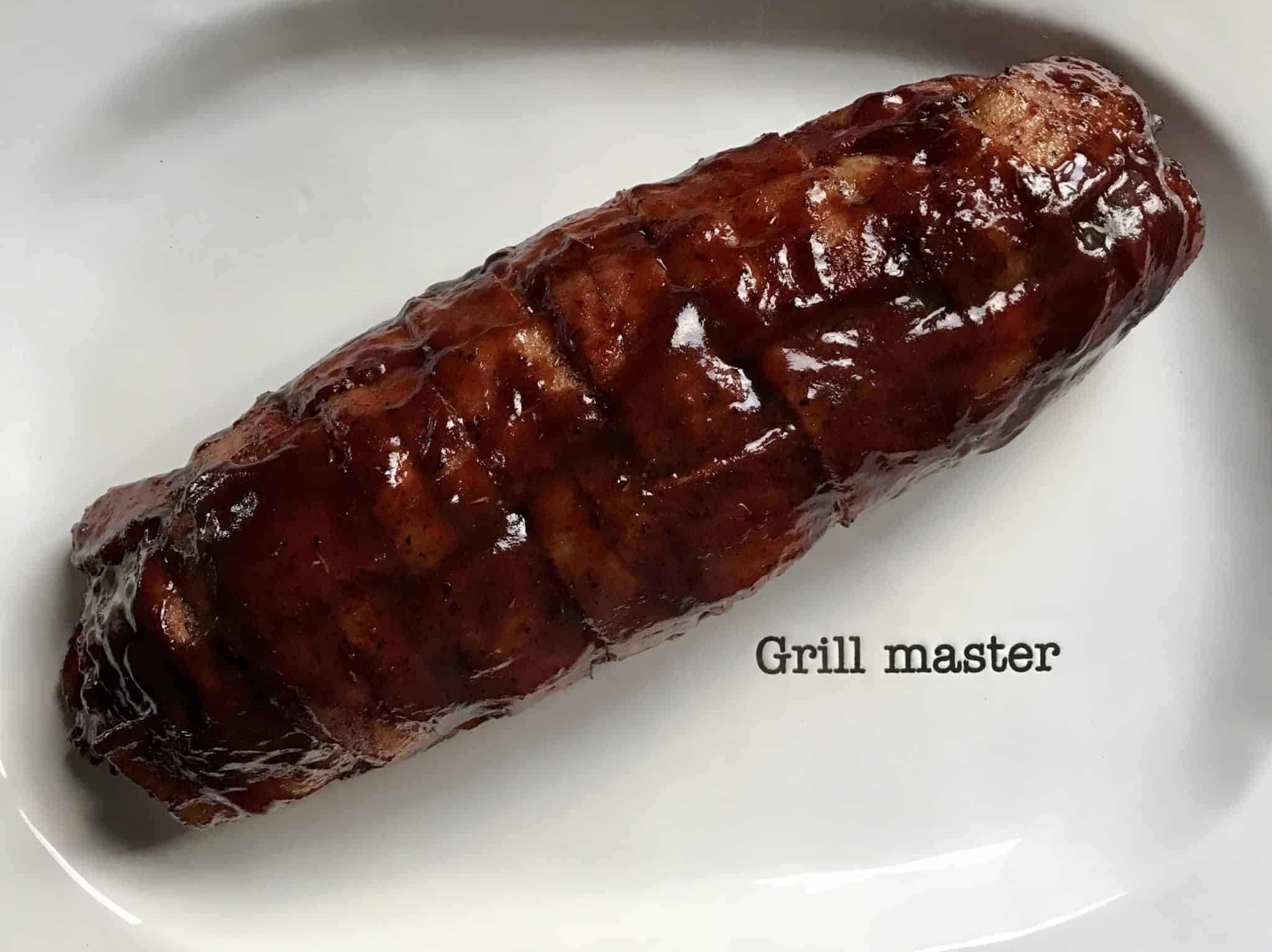Bacon explosion sauced on white platter that says "grill master" overhead shot