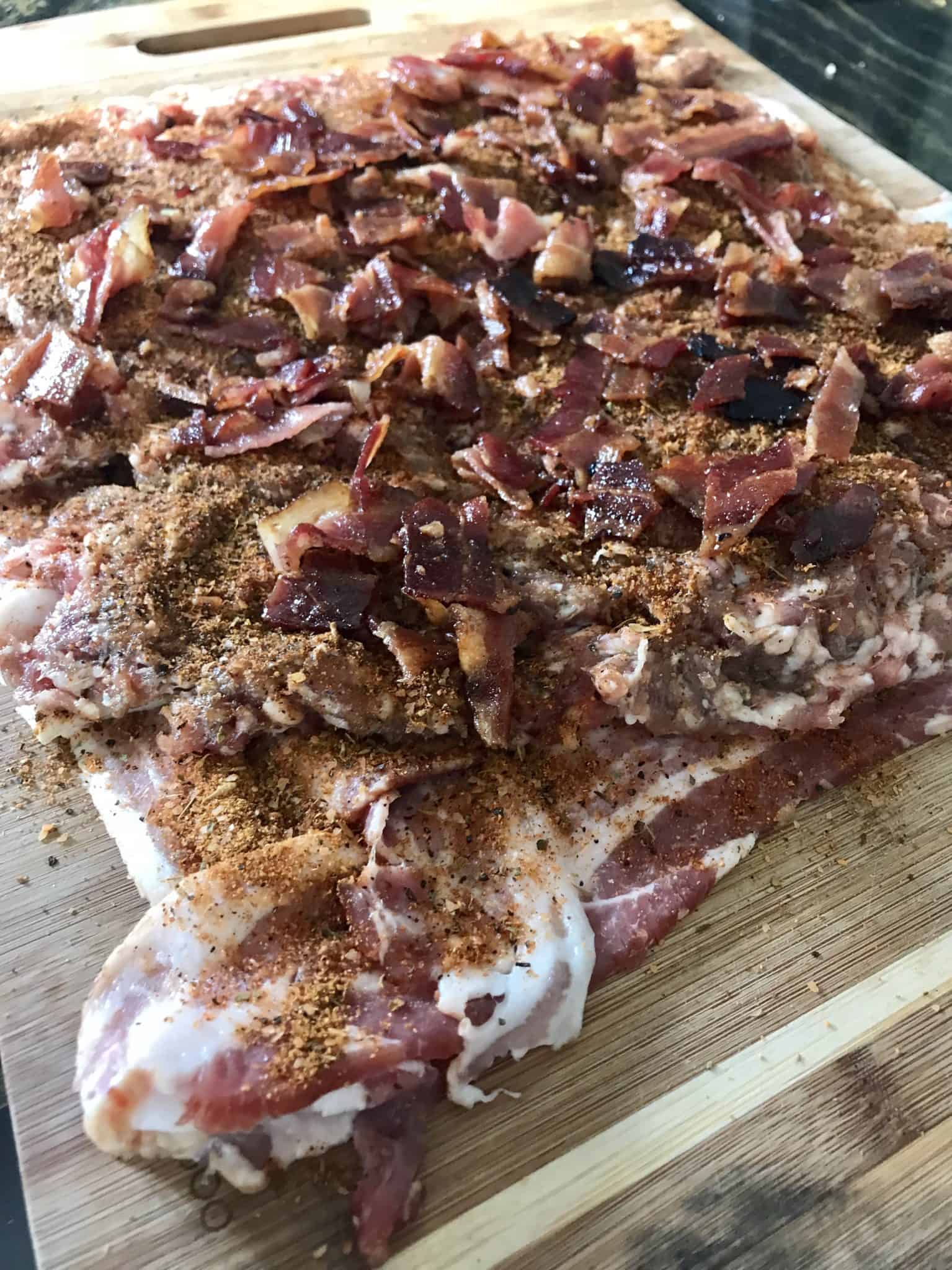 Bacon weave topped with all ingredients on wooden cutting board side view