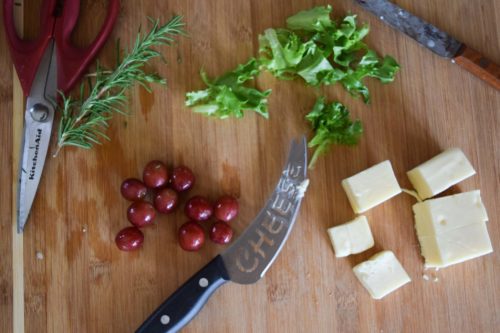 Grape, Fontina, Blue Cheese, Arugula Flatbread ingredients on wooden cutting board overhead shot