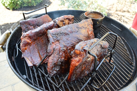 ribs being smoked in a rib rack on weber grill close up view