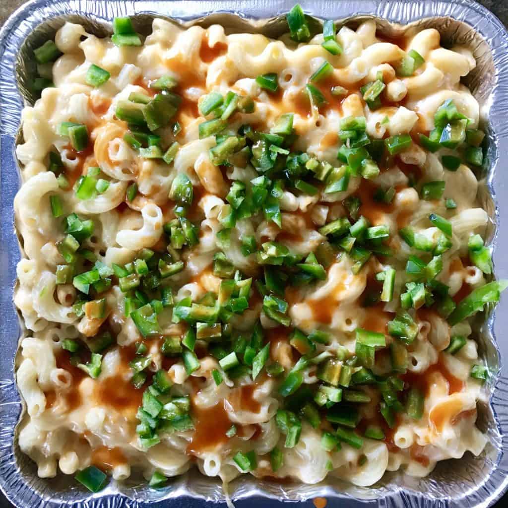 Smoked Mac and cheese topped with hot sauce and jalapeños