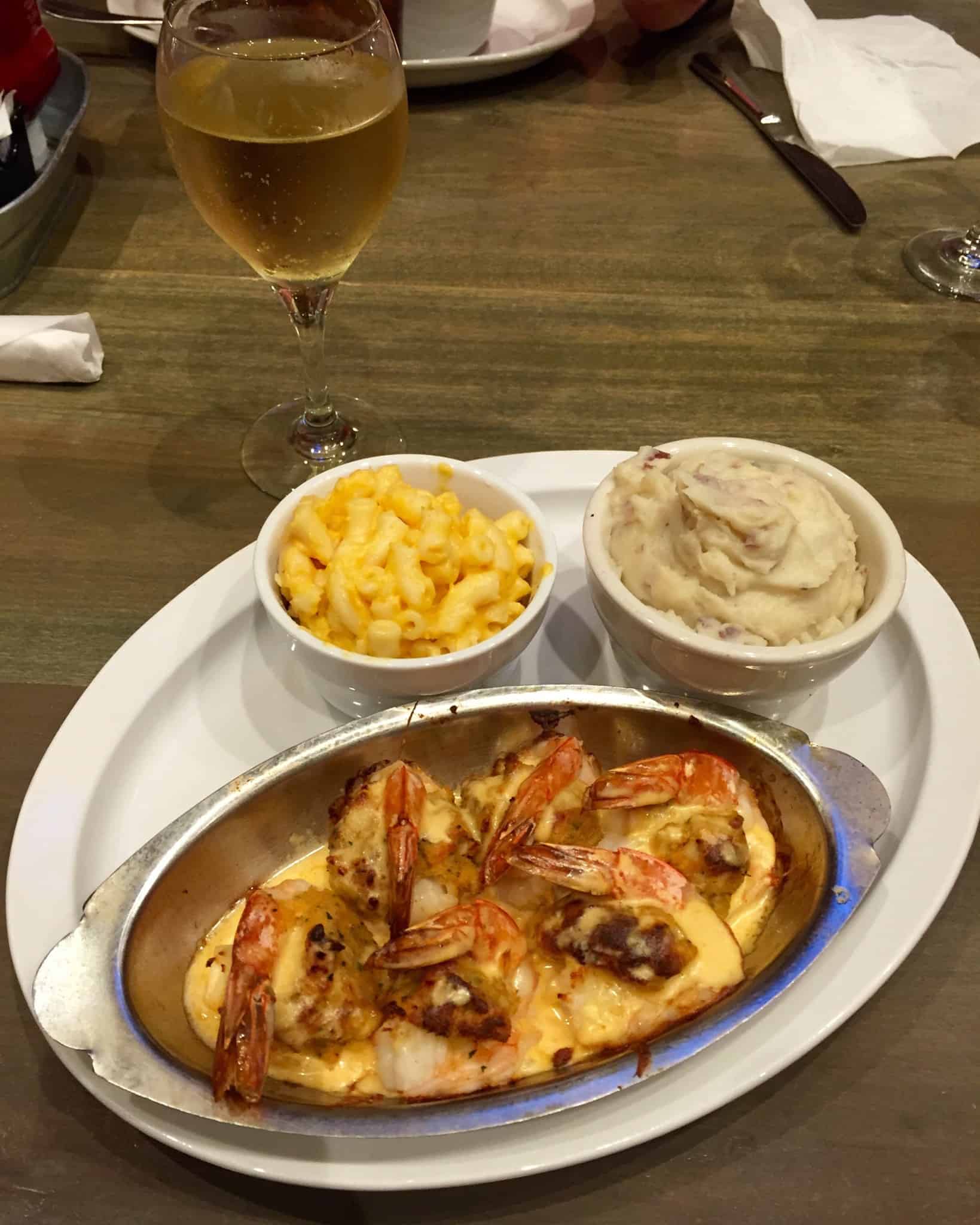 Plate of stuffed shrimp mac and cheese mashed potatoes and a glass of wine
