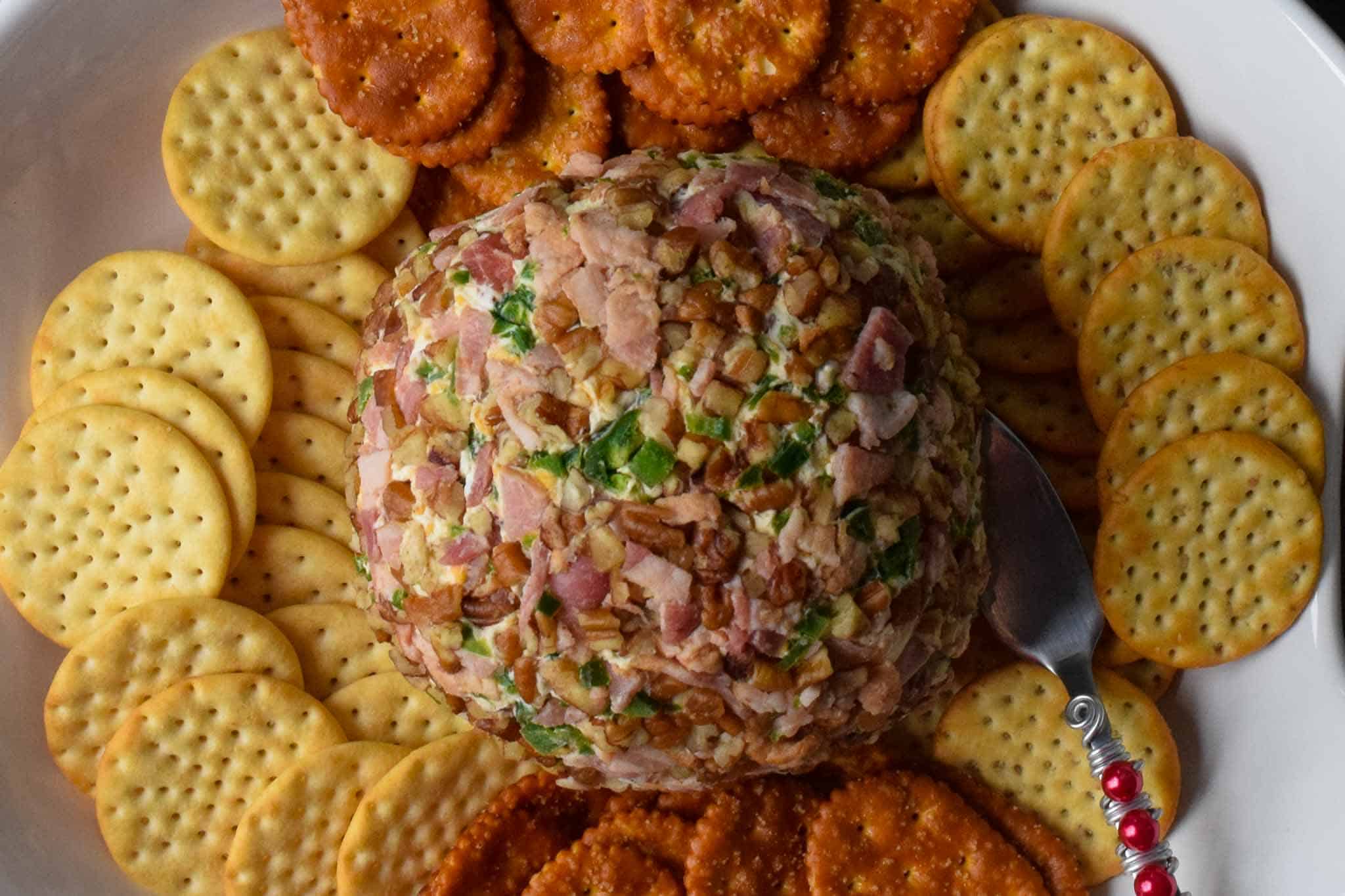 Jalapeno Bacon Cheeseball on white platter surrounded by various crackers overhead shot
