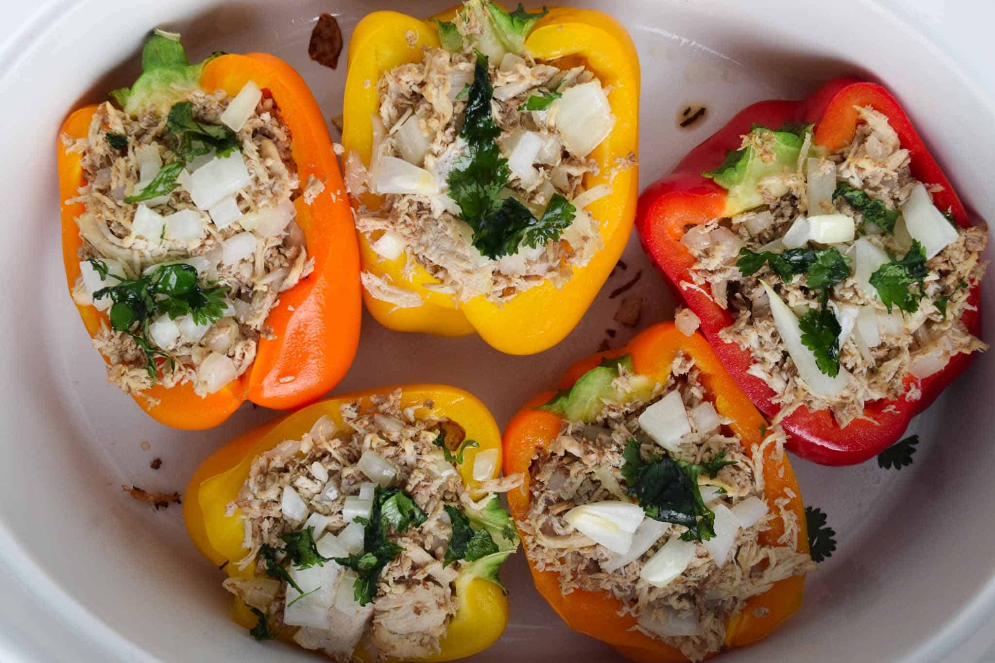 cooked chicken stuffed peppers in white dish topped with cilantro overhead shot