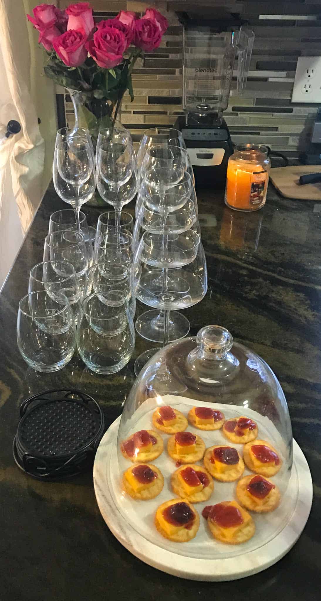 appetizer on globe platter with wine glasses lined up behind it and candle burning in background
