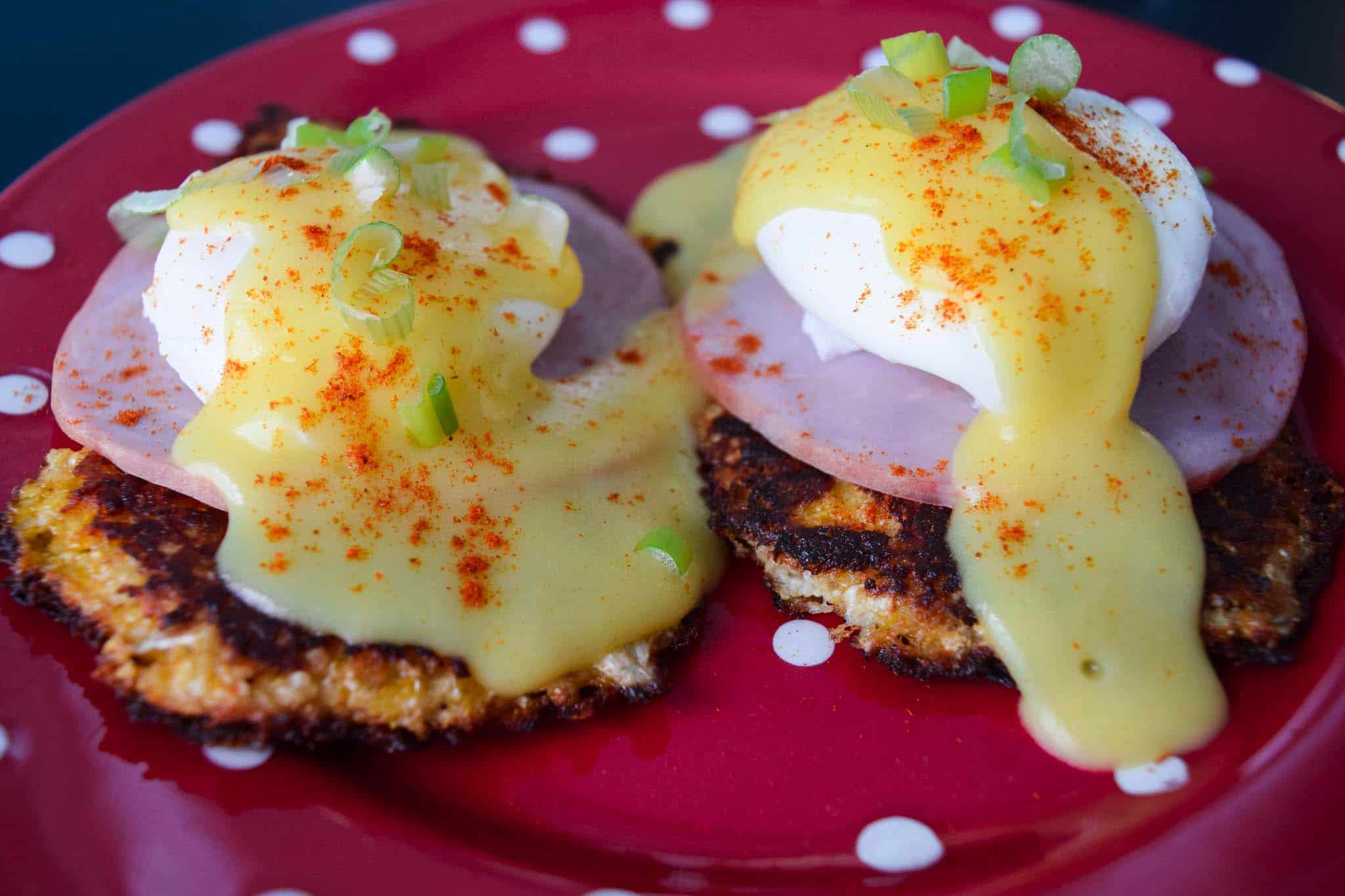 cauliflower benedict on red plate topped with hollandaise sauce close up
