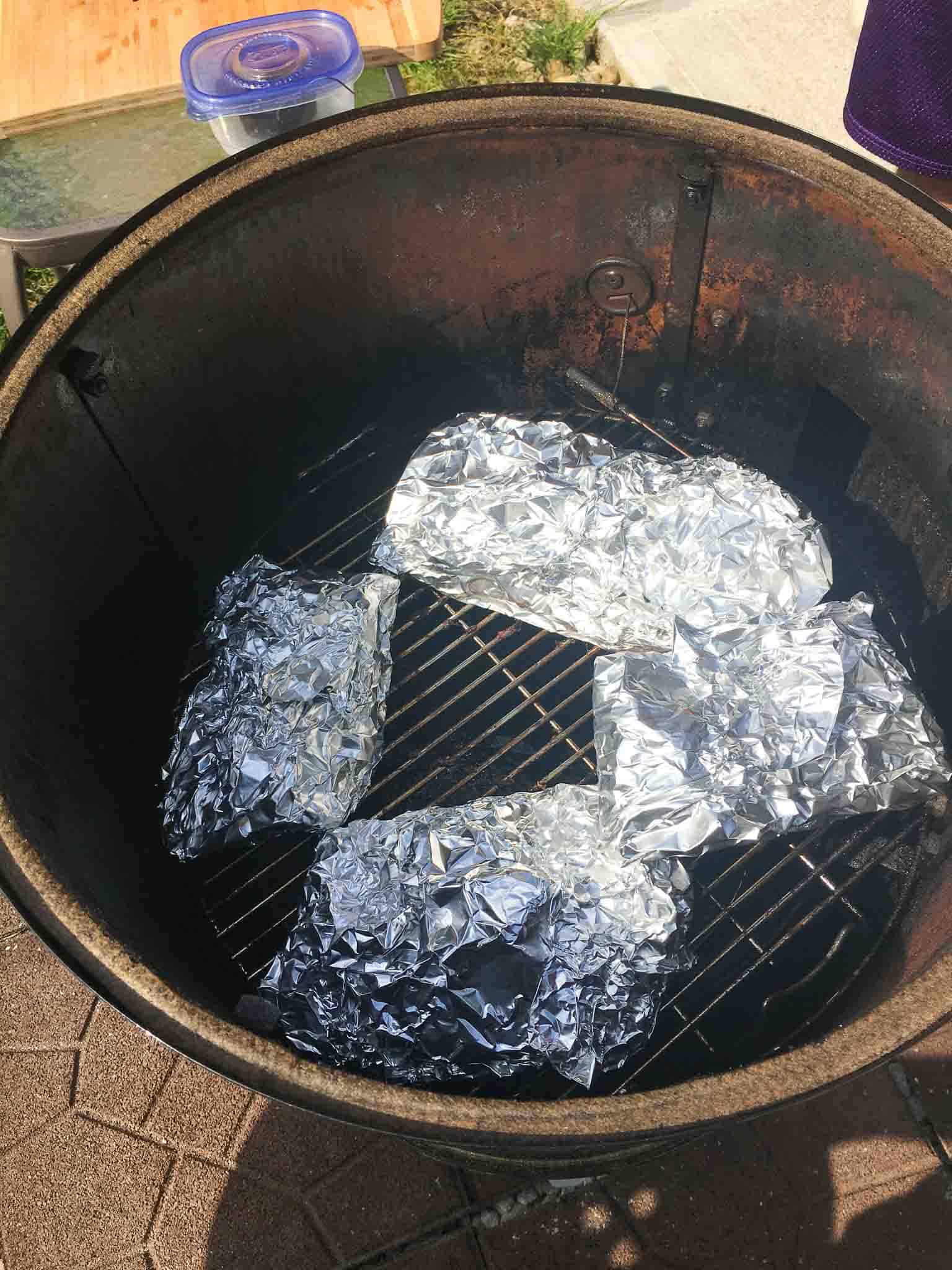 ribs wrapped in foil inside of weber grill overhead shot