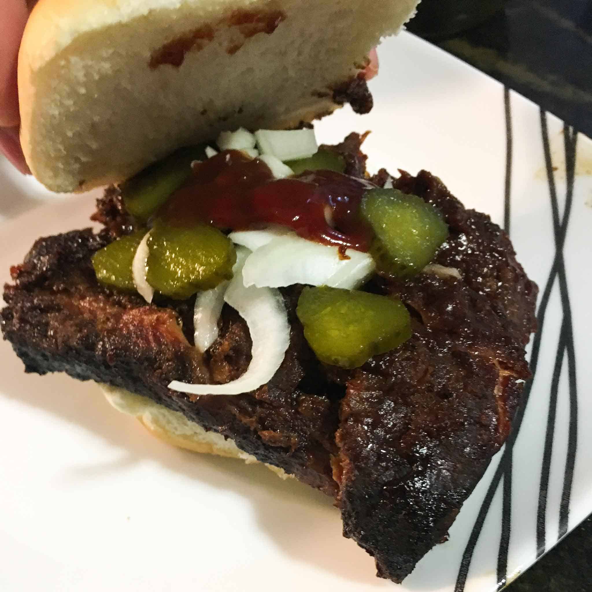 ribs made into a mcrib style sandwich with pickles and onions on top