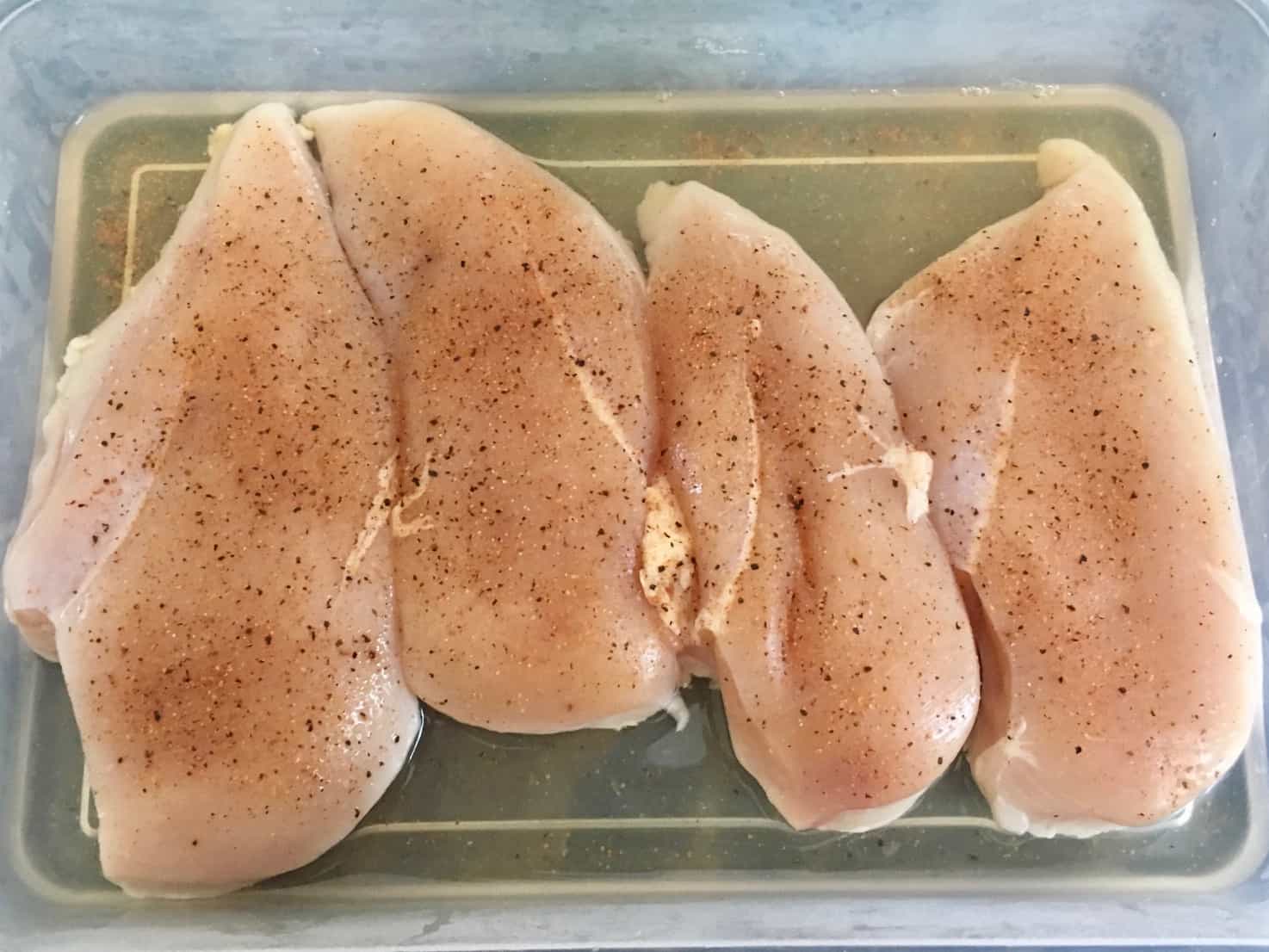 Chicken breasts brining in container of water overhead shot