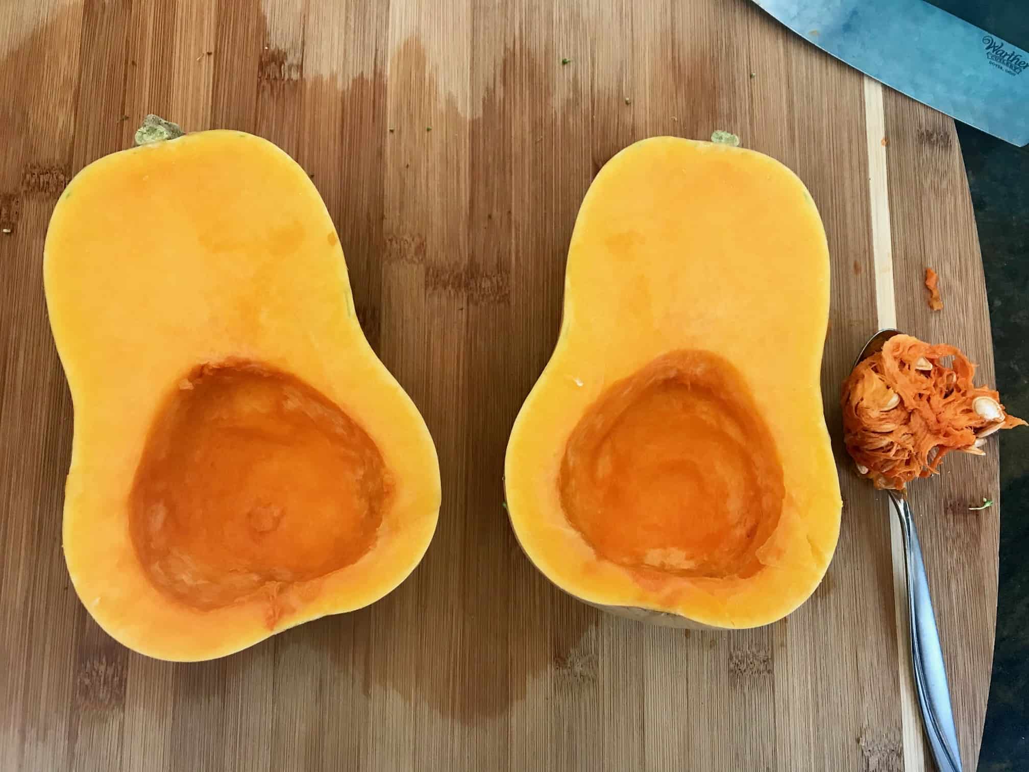 Butternut squash on cutting board cut in half with seeds removed