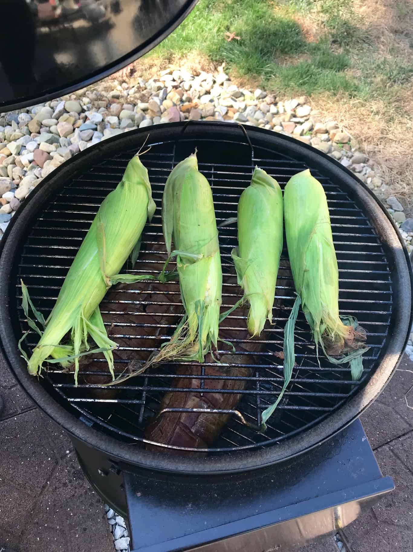 Corn on the cob still in husks on weber grill 