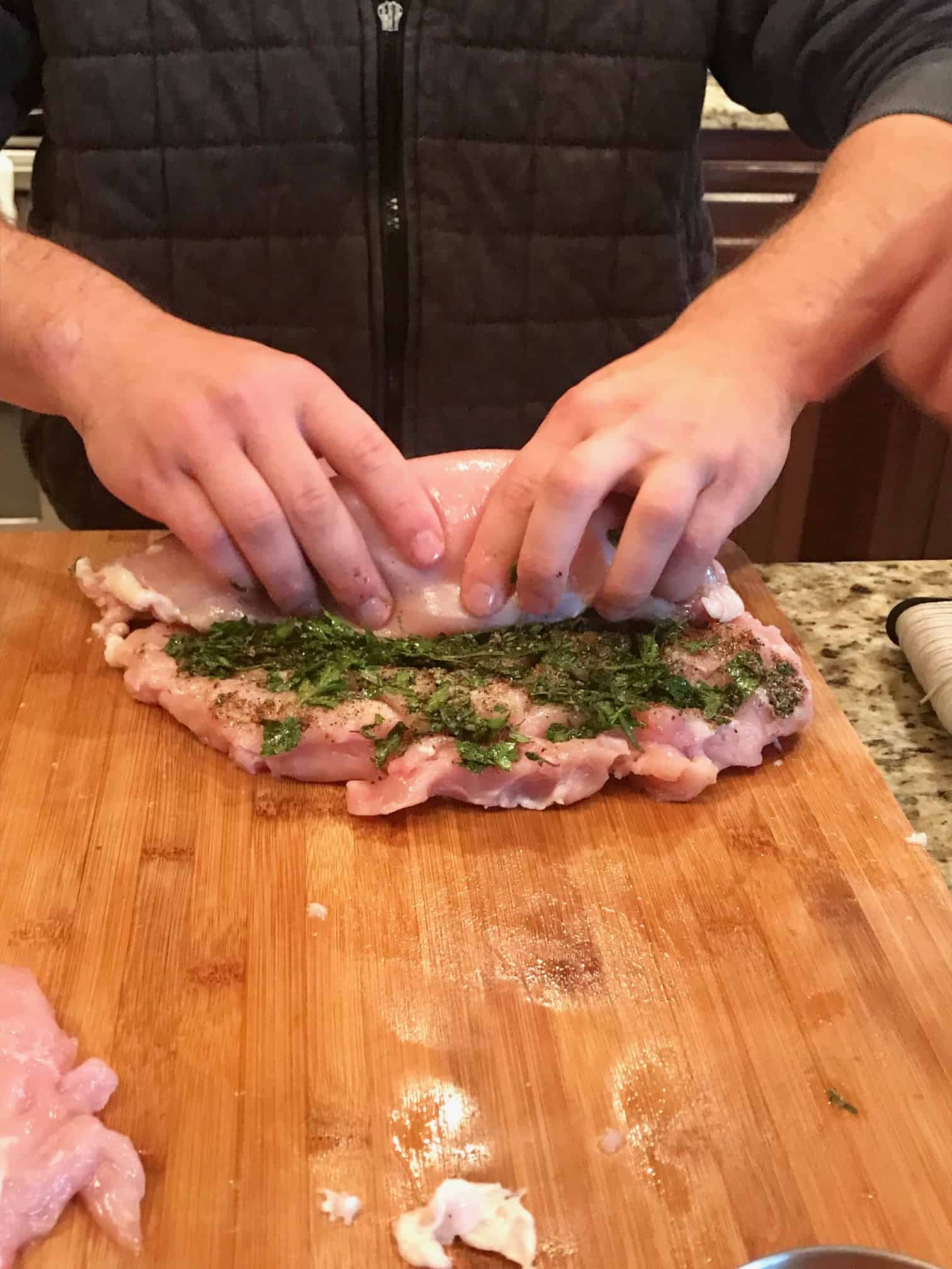 Deboned Turkey topped with herbs being rolled up side view