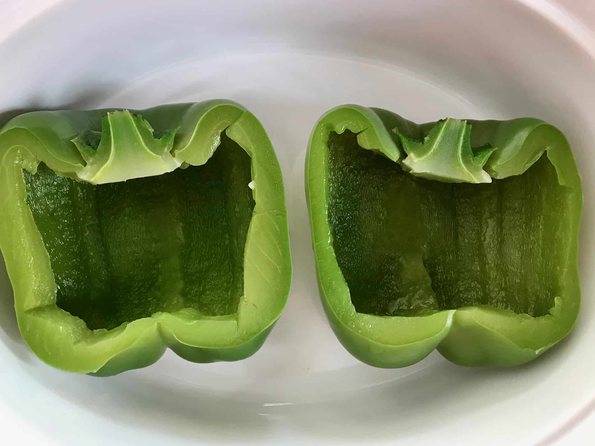 Green pepper sliced in half in white bowl overhead shot