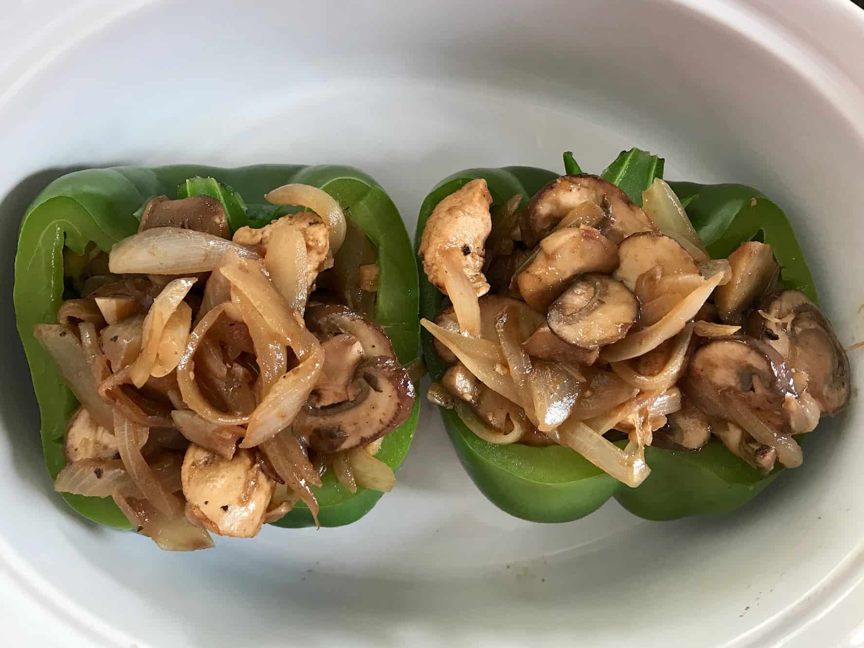Green pepper sliced in half stuffed with mushrooms and onions in white bowl overhead shot