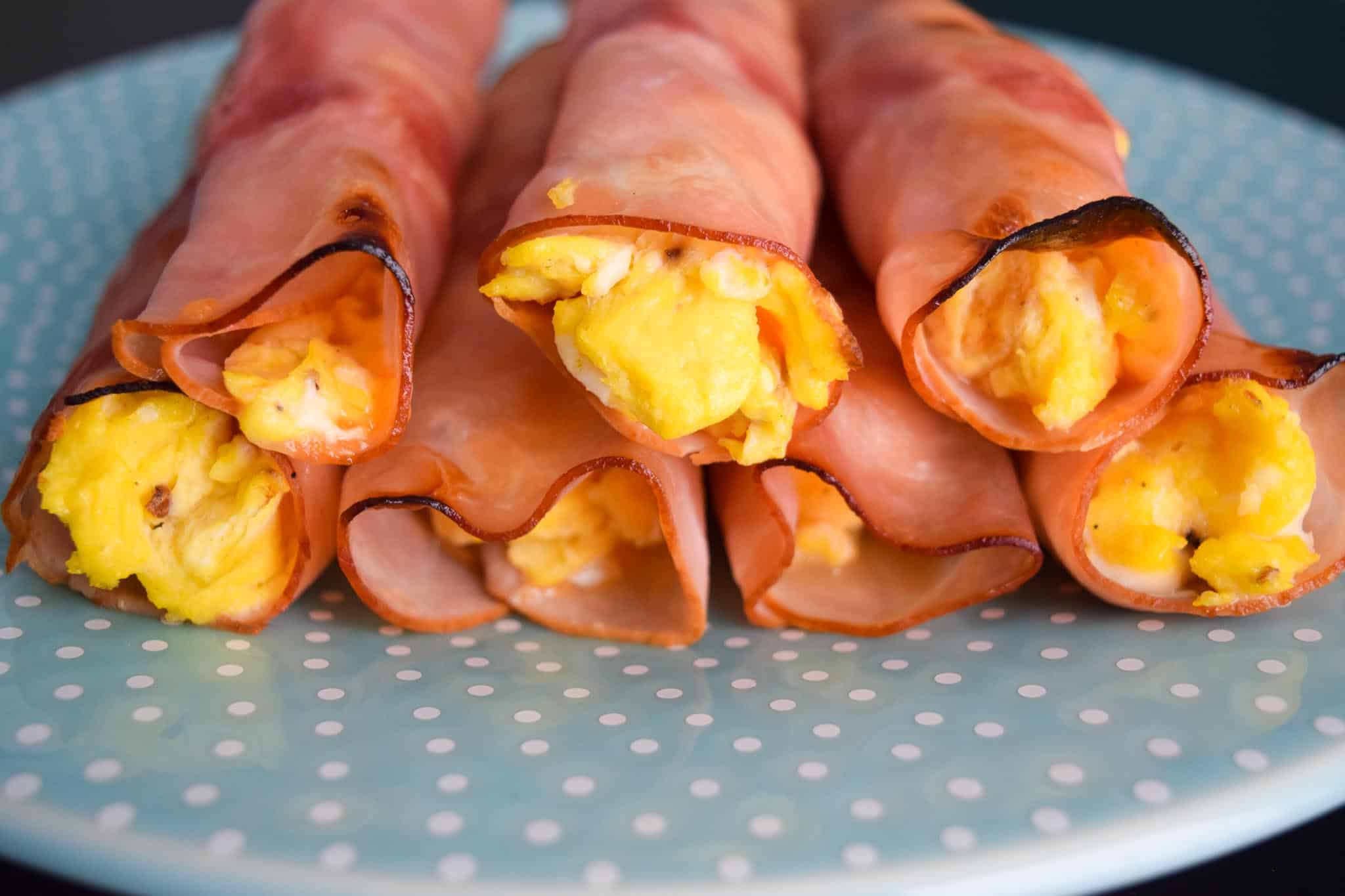 Ham Egg and Cheese Roll-Ups stacked on blue plate close up