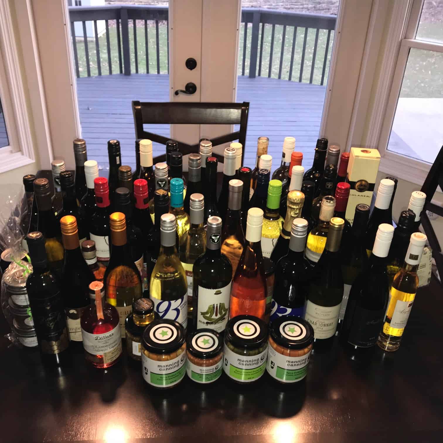 Giant collection of wine bottles lined up on kitchen table 