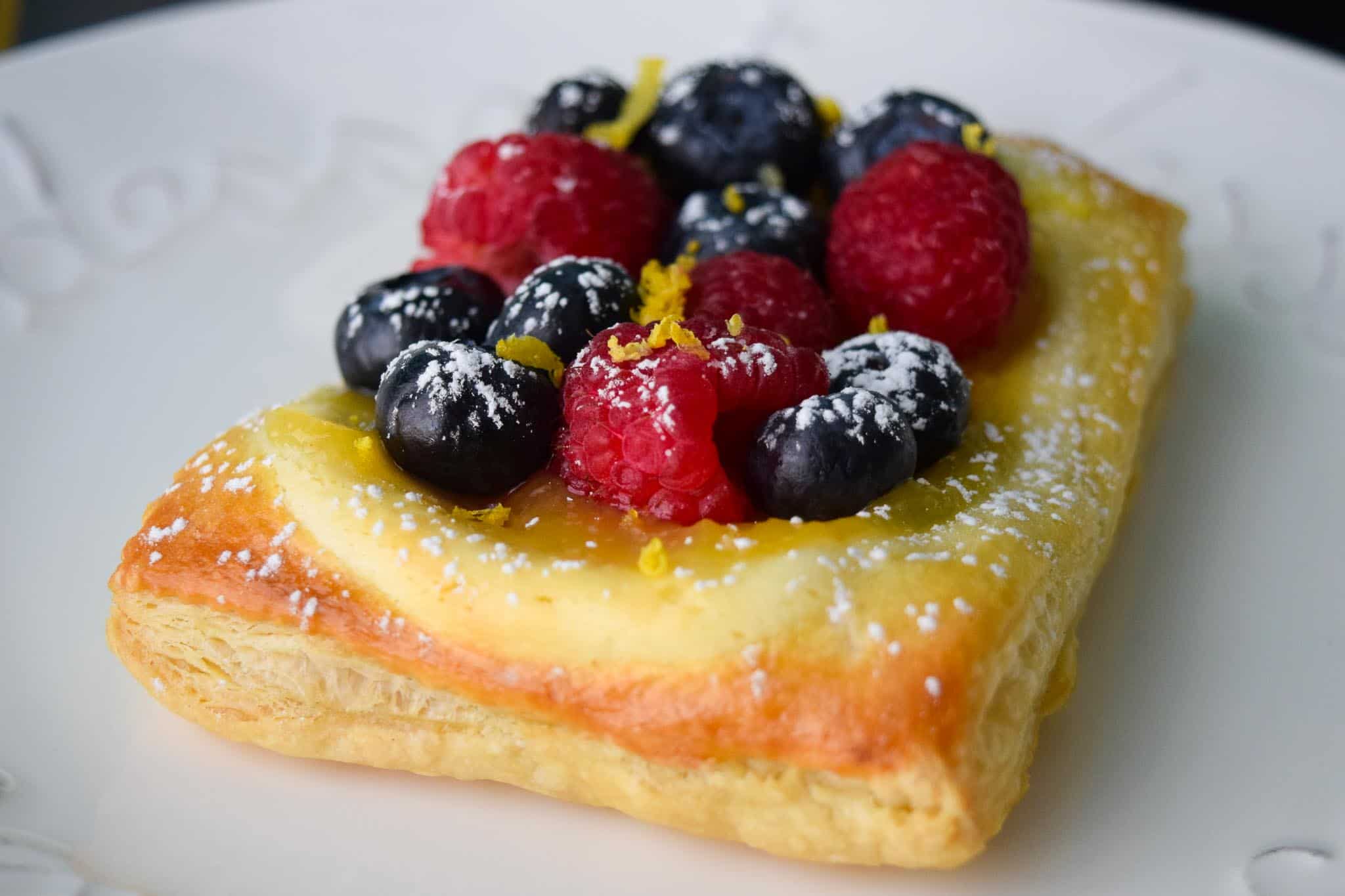 Lemon and Berry Cheesecake Puff on white dessert plate side view