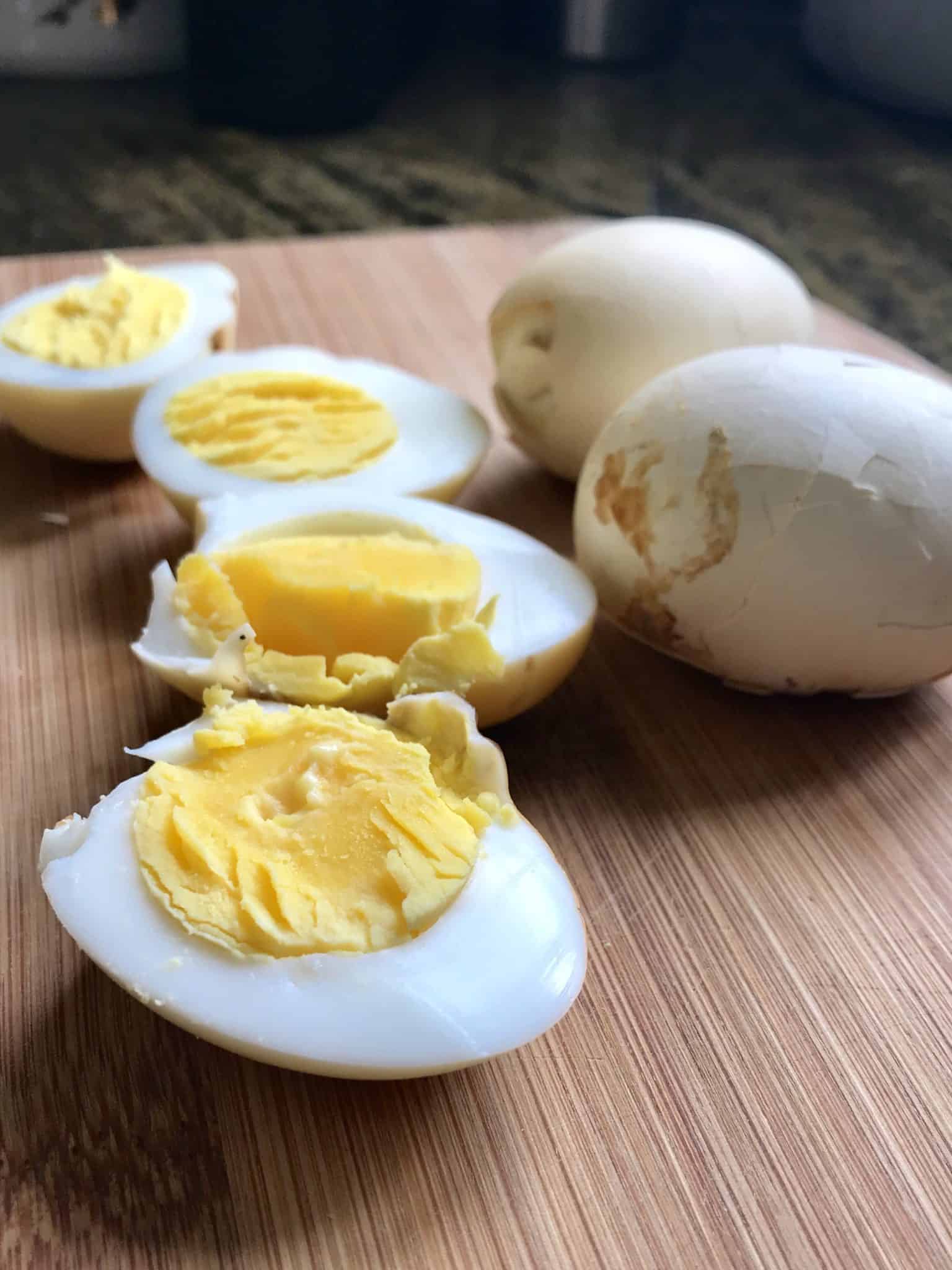 Smoked Eggs sliced in half sitting on wooden cutting board close up view