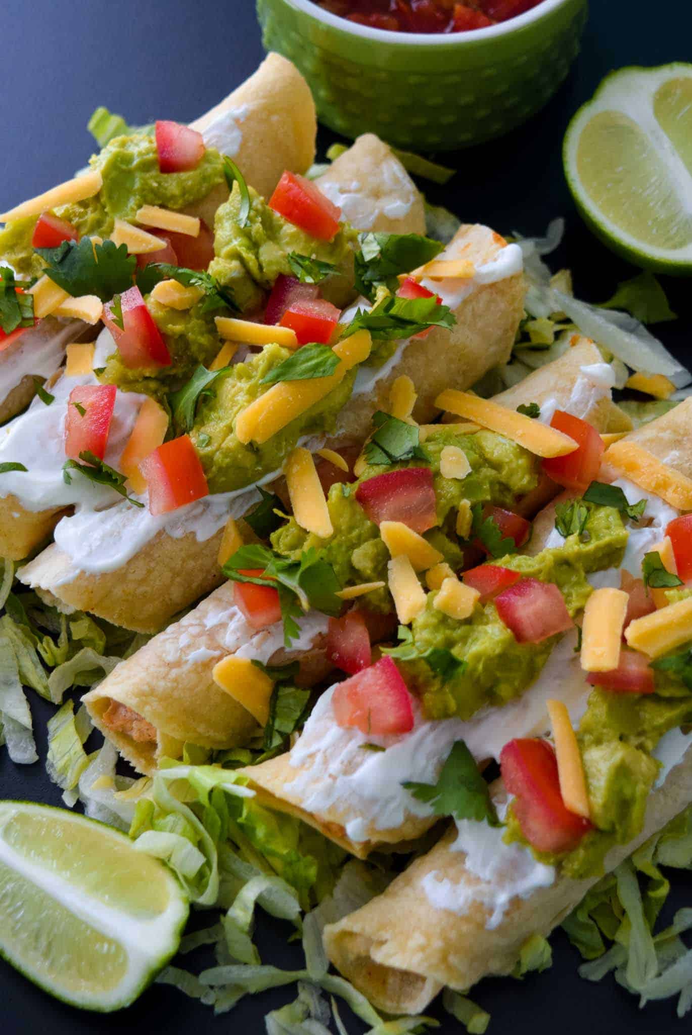 Baked Chicken Taquitos with toppings ready to be served close up