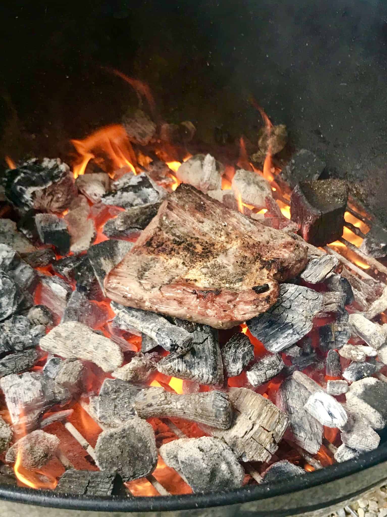 Steak being cooked directly on top of coals