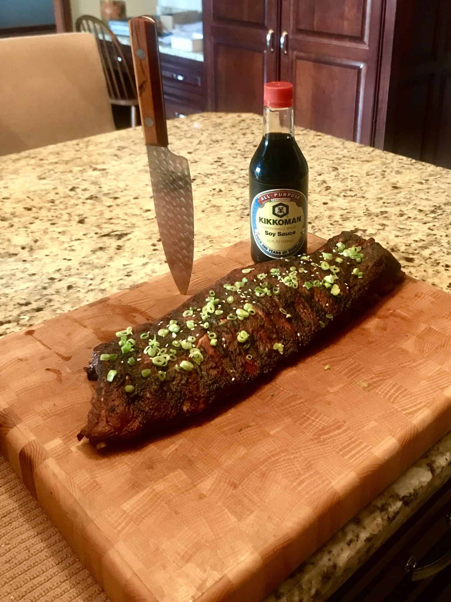 Spicy Asian Ribs on wooden cutting board with soy sauce and knife in background