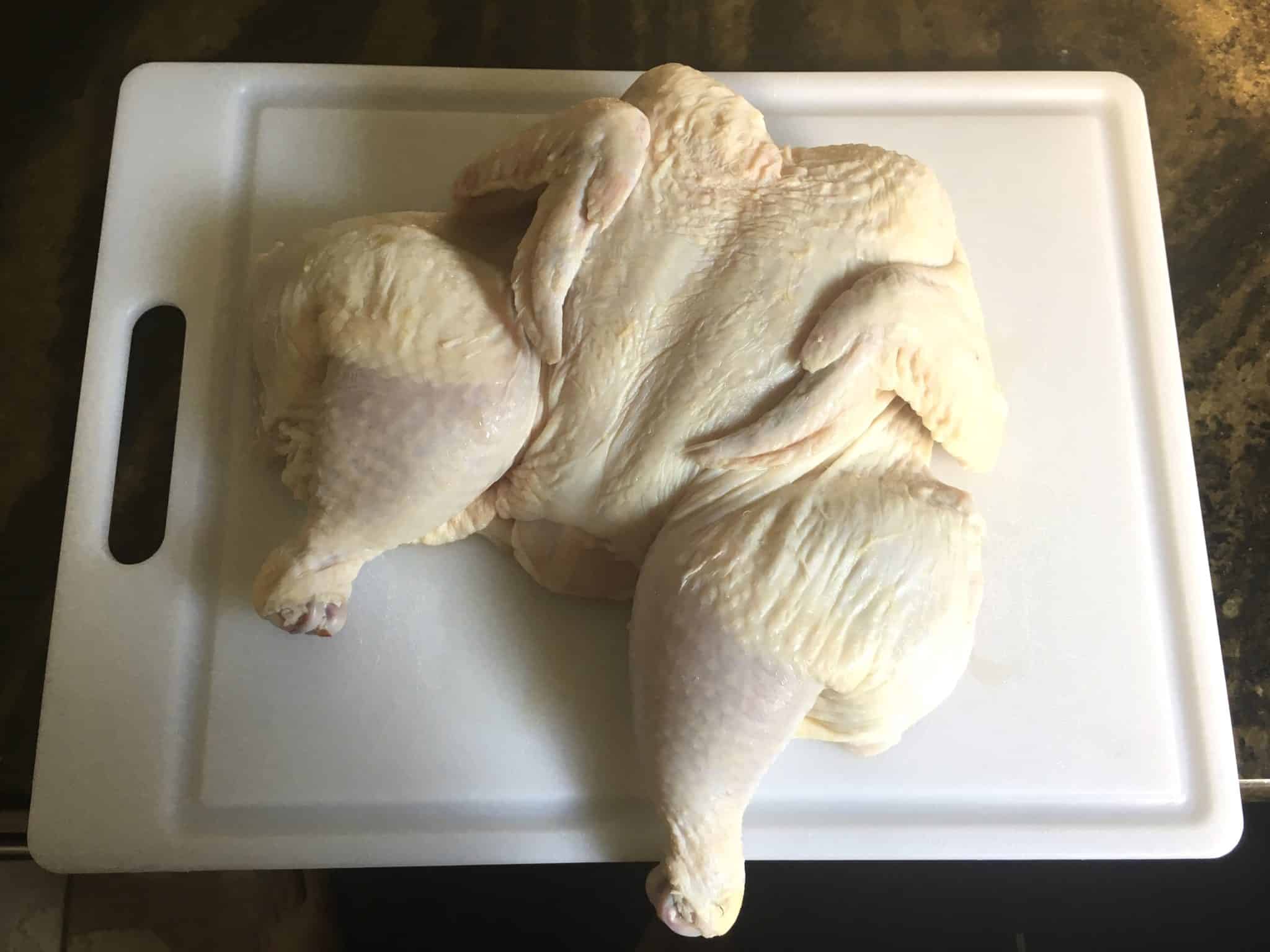 Spatchcocked chicken on white cutting board