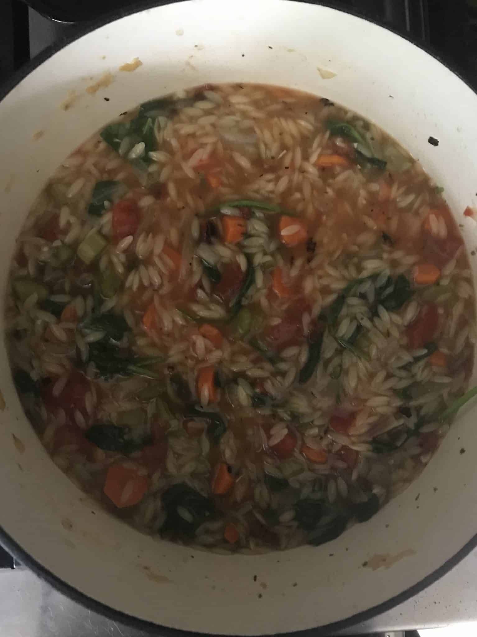 Orzo added to soup pot overhead shot