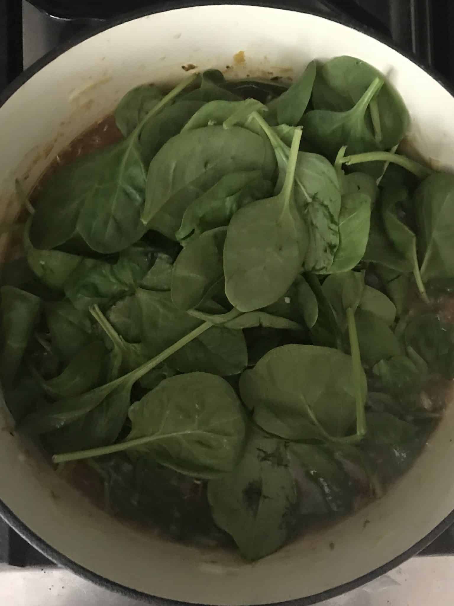 Spinach added to soup pot overhead shot