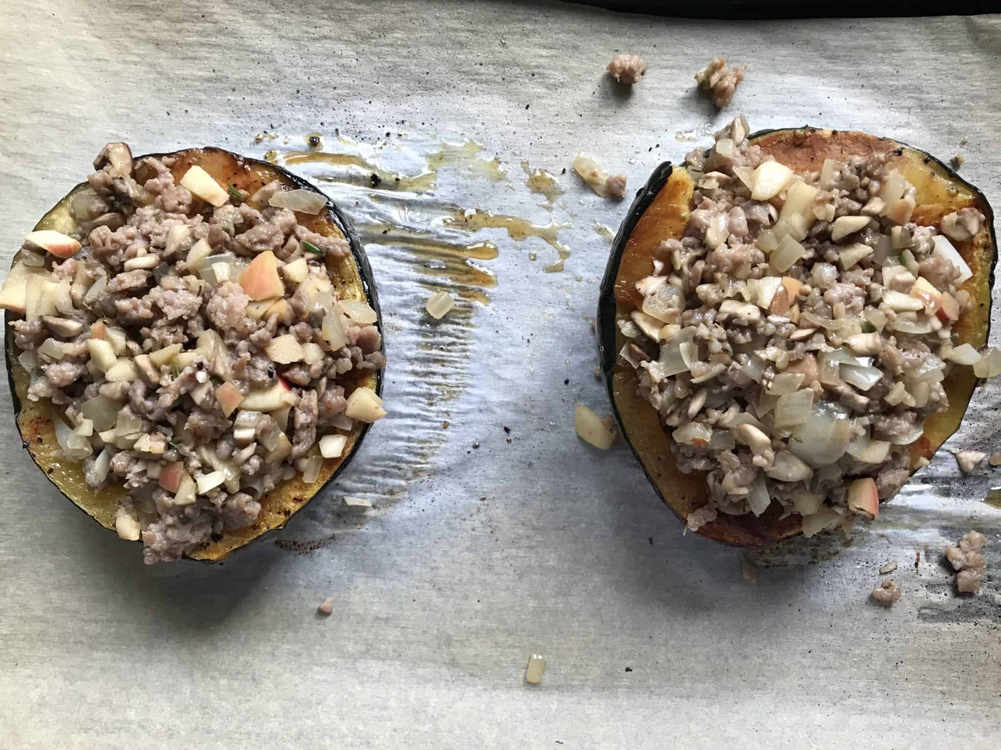 Acorn Squash stuffed with sausage and apple mixture on baking sheet