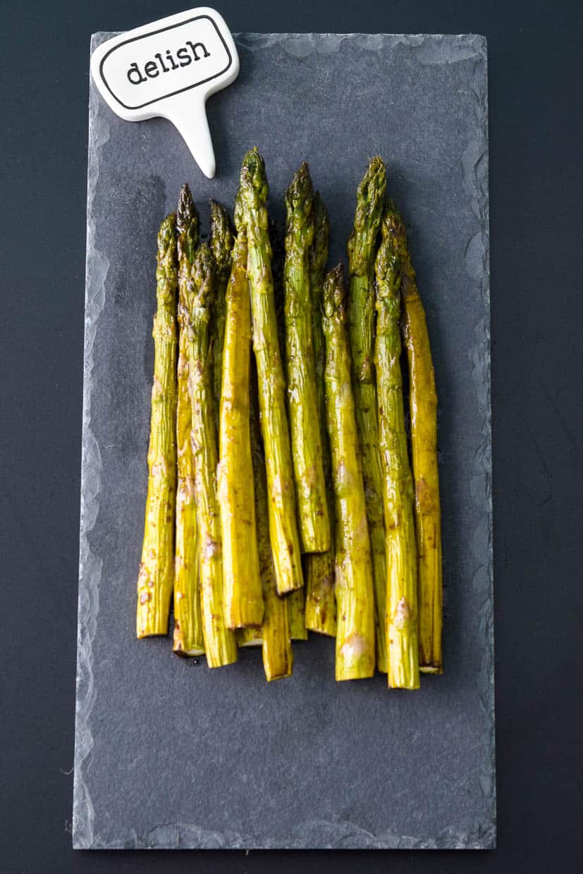 Easy Roasted Asparagus on slate platter with delish sign above it