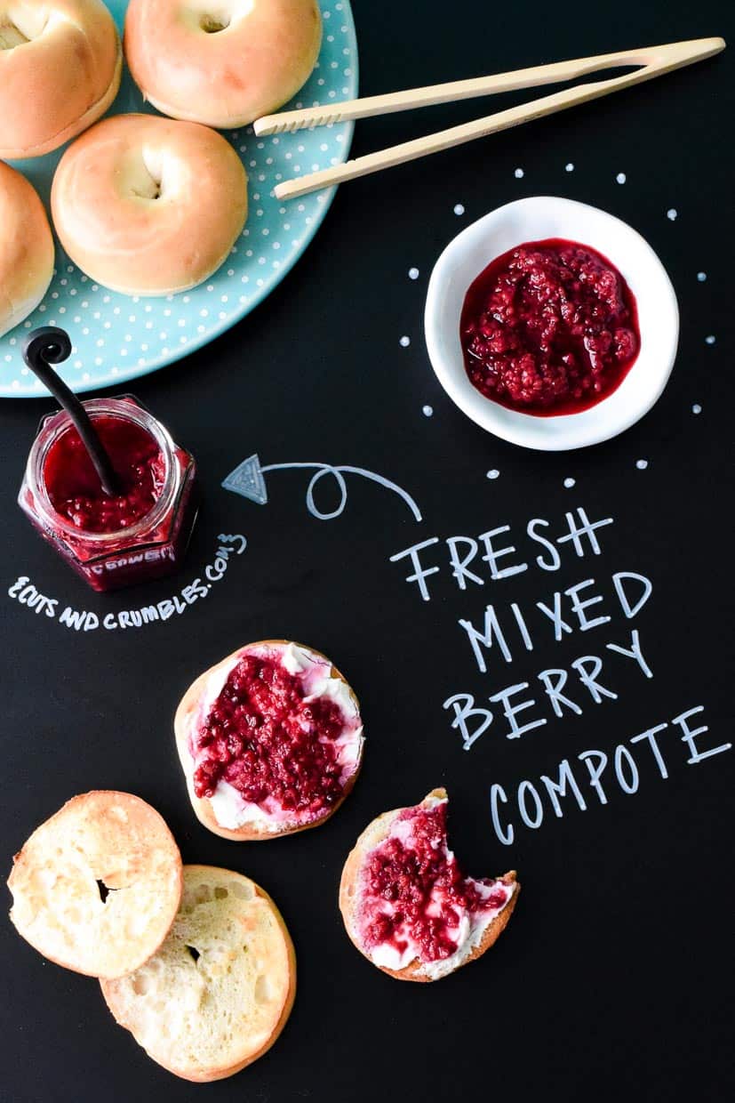 Fresh Mixed Berry Compote on mini bagels on black chalkboard with title written in chalk