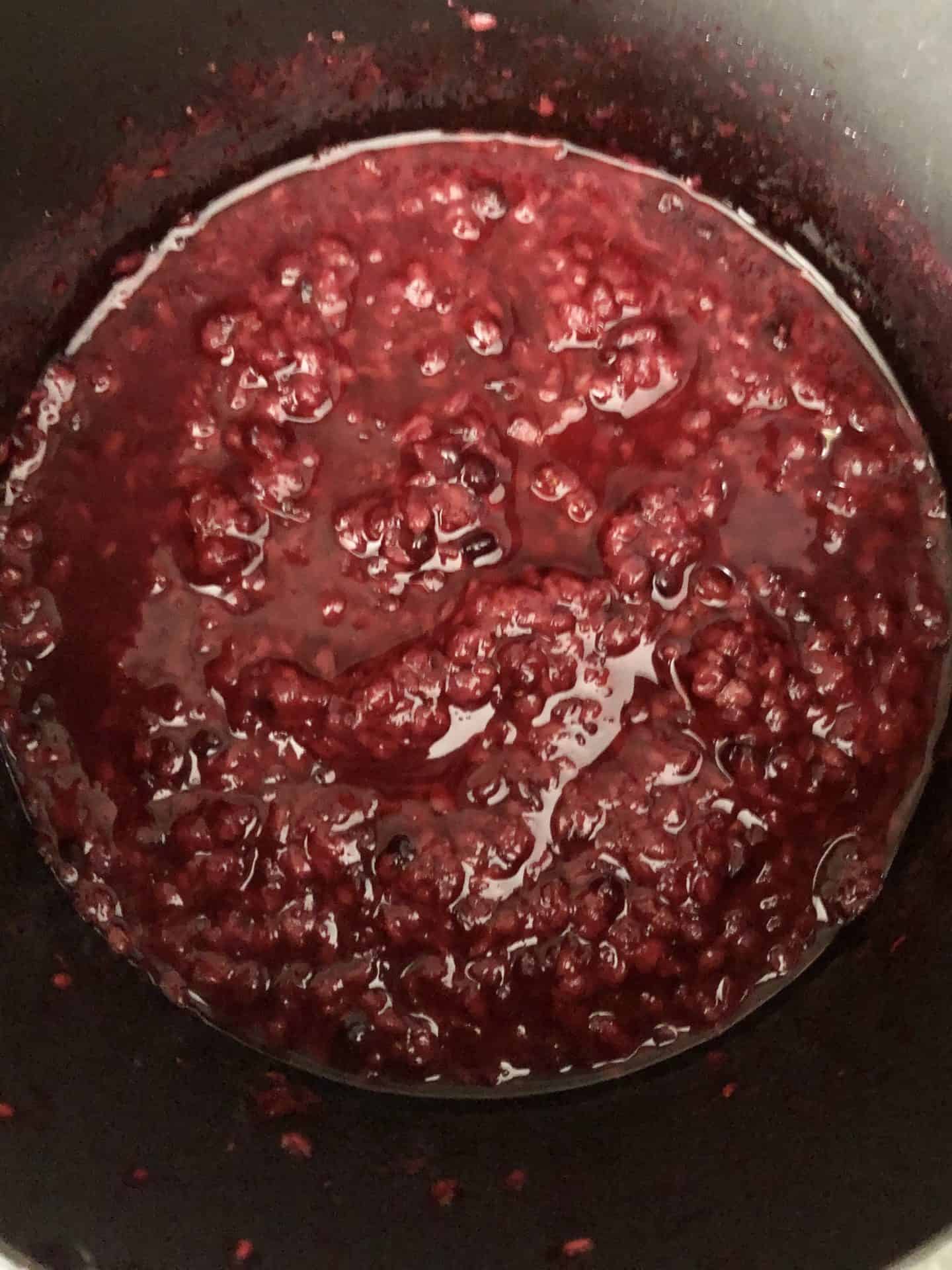 Raspberries and blackberries cooked down in pot 