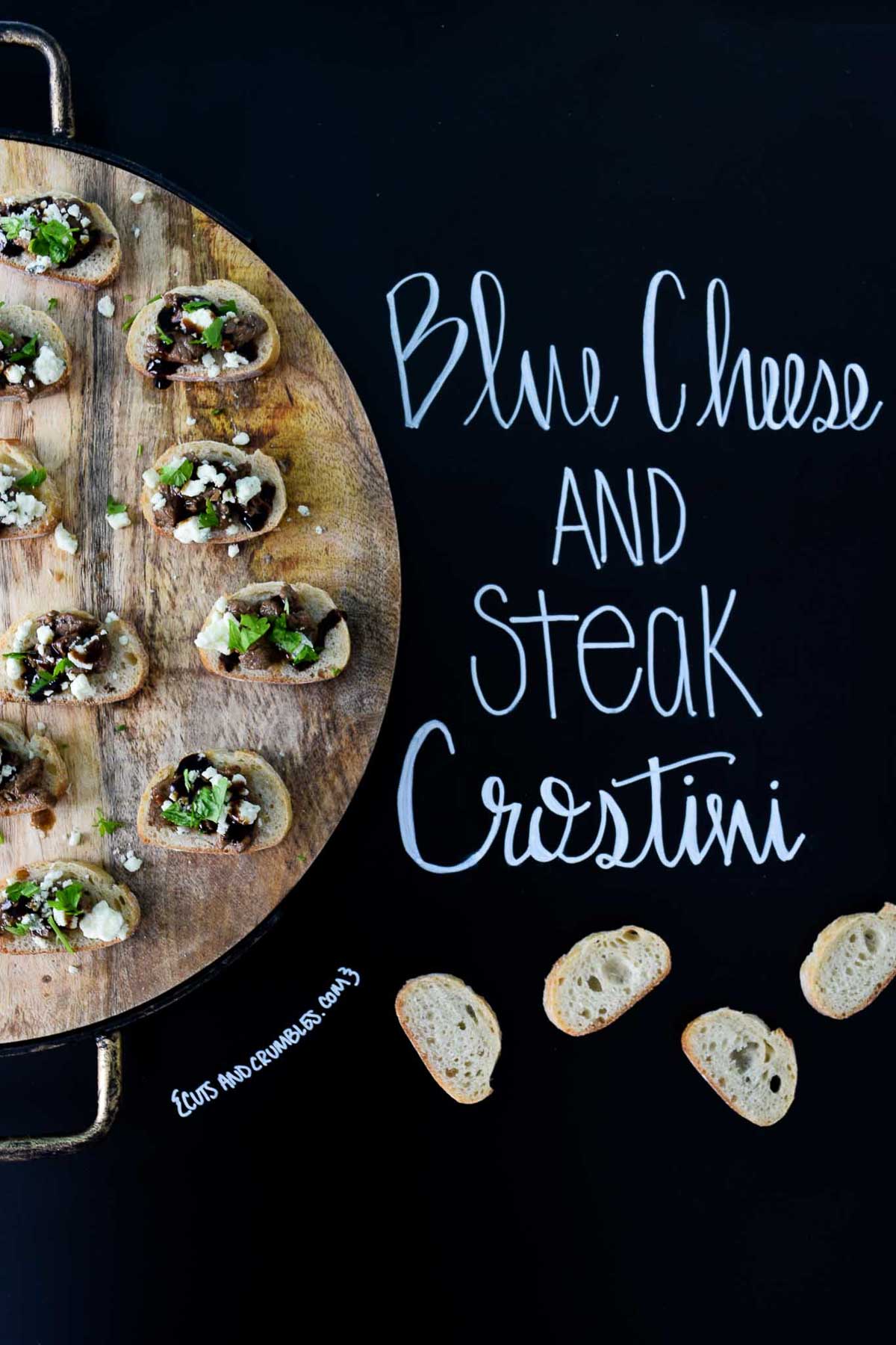 Blue Cheese and Steak Crostini on wooden platter with title written on chalkboard