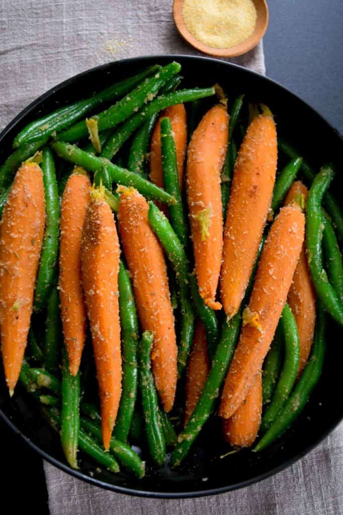 overhead shot of black bowl with sautéed carrots and green beans 
